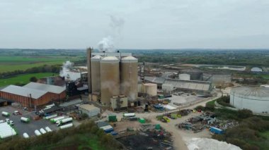 Cinematic Flight Over Vast British Sugar Factory Infrastructure With Large Storage Silos And Exhaust Plumes