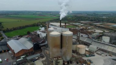 Cinematic Flight Over Vast British Sugar Factory Infrastructure With Large Storage Silos And Exhaust Plumes