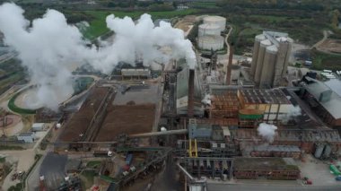 Cinematic Flight Over Vast British Sugar Factory Infrastructure With Large Storage Silos And Exhaust Plumes