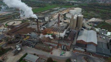 Cinematic Flight Over Vast British Sugar Factory Infrastructure With Large Storage Silos And Exhaust Plumes