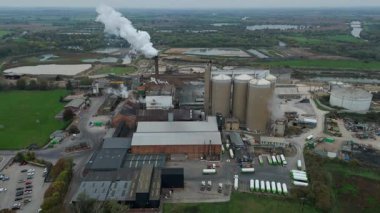 Cinematic Flight Over Vast British Sugar Factory Infrastructure With Large Storage Silos And Exhaust Plumes