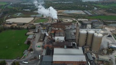 Cinematic Flight Over Vast British Sugar Factory Infrastructure With Large Storage Silos And Exhaust Plumes