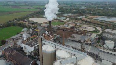 Cinematic Flight Over Vast British Sugar Factory Infrastructure With Large Storage Silos And Exhaust Plumes