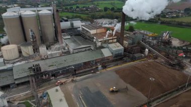 Cinematic Flight Over Vast British Sugar Factory Infrastructure With Large Storage Silos And Exhaust Plumes