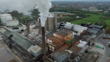 Cinematic Flight Over Vast British Sugar Factory Infrastructure With Large Storage Silos And Exhaust Plumes