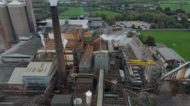 Cinematic Flight Over Vast British Sugar Factory Infrastructure With Large Storage Silos And Exhaust Plumes