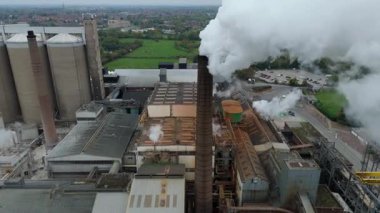 Cinematic Flight Over Vast British Sugar Factory Infrastructure With Large Storage Silos And Exhaust Plumes