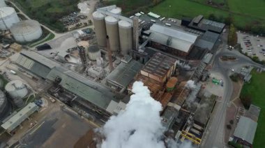 Cinematic Flight Over Vast British Sugar Factory Infrastructure With Large Storage Silos And Exhaust Plumes