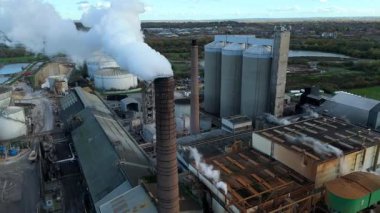 Cinematic Flight Over Vast British Sugar Factory Infrastructure With Large Storage Silos And Exhaust Plumes
