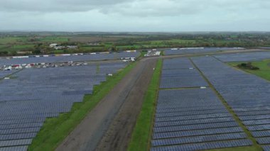 İngiliz kırsal kesimindeki eski RAF Üs Taksiyollarında inşa edilen Büyük Endüstriyel Güneş Çiftliği Altyapısı Üzerine Sinematik Uçuş