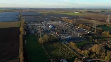 Günbatımında temiz enerji entegrasyonunu gösteren Cambridgeshire İngiltere 'deki geniş Burwell alt istasyonu ve güneş enerjisi santralinin hava görüntüsü.