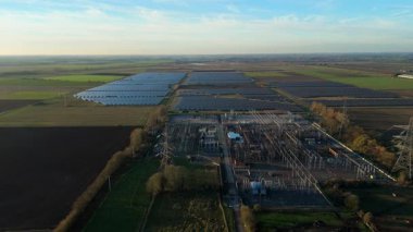 Günbatımında temiz enerji entegrasyonunu gösteren Cambridgeshire İngiltere 'deki geniş Burwell alt istasyonu ve güneş enerjisi santralinin hava görüntüsü.