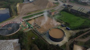 Bury St Edmunds UK 'deki İngiliz Şeker Fabrikası' nın hava aracı görüntüsünde duman bulutları ve şeker pancarı işleme için endüstriyel silolar yer alıyor..