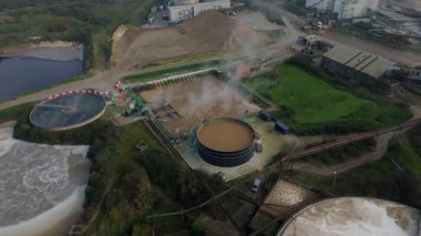 Bury St Edmunds UK 'deki İngiliz Şeker Fabrikası' nın hava aracı görüntüsünde duman bulutları ve şeker pancarı işleme için endüstriyel silolar yer alıyor..