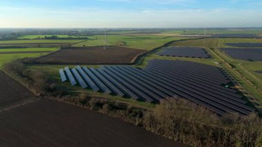 Birleşik Krallık 'taki altın saat boyunca gün batımında muazzam bir güneş enerjisi santralinin çarpıcı hava manzarası.