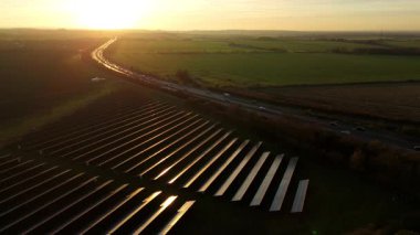 Birleşik Krallık 'taki altın saat boyunca gün batımında muazzam bir güneş enerjisi santralinin çarpıcı hava manzarası.
