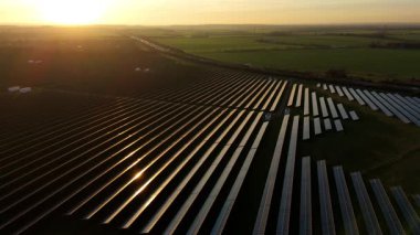 Birleşik Krallık 'taki altın saat boyunca gün batımında muazzam bir güneş enerjisi santralinin çarpıcı hava manzarası.