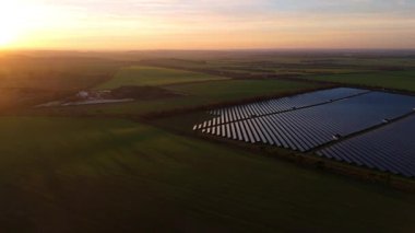 Birleşik Krallık 'taki altın saat boyunca gün batımında muazzam bir güneş enerjisi santralinin çarpıcı hava manzarası.