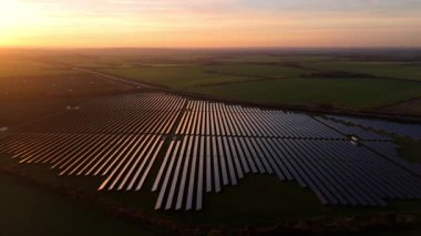 Birleşik Krallık 'taki altın saat boyunca gün batımında muazzam bir güneş enerjisi santralinin çarpıcı hava manzarası.