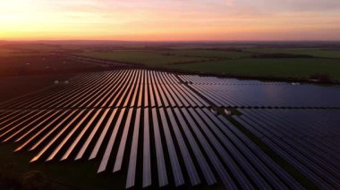 Birleşik Krallık 'taki altın saat boyunca gün batımında muazzam bir güneş enerjisi santralinin çarpıcı hava manzarası.