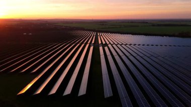 Birleşik Krallık 'taki altın saat boyunca gün batımında muazzam bir güneş enerjisi santralinin çarpıcı hava manzarası.