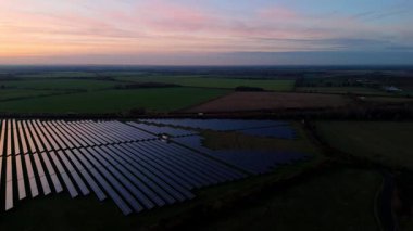 Birleşik Krallık 'taki altın saat boyunca gün batımında muazzam bir güneş enerjisi santralinin çarpıcı hava manzarası.