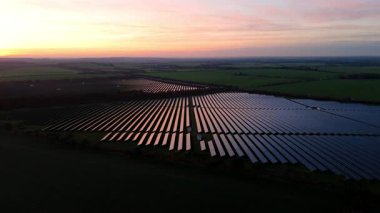 Birleşik Krallık 'taki altın saat boyunca gün batımında muazzam bir güneş enerjisi santralinin çarpıcı hava manzarası.