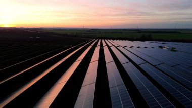 Birleşik Krallık 'taki altın saat boyunca gün batımında muazzam bir güneş enerjisi santralinin çarpıcı hava manzarası.