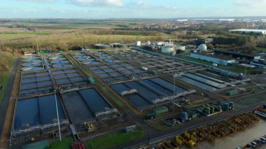 Büyük bir İngiliz kanalizasyon arıtma tesisinin hava aracı görüntüsü dairesel tortu tankları ve endüstriyel atık su işleme birimlerini gösteriyor..