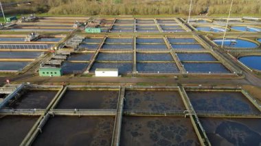 Büyük bir İngiliz kanalizasyon arıtma tesisinin hava aracı görüntüsü dairesel tortu tankları ve endüstriyel atık su işleme birimlerini gösteriyor..