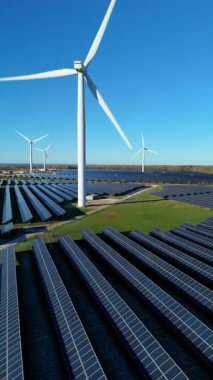 Birleşik Krallık 'taki büyük bir hibrit enerji parkının hava aracı görüntüsü, sürdürülebilir enerji için endüstriyel rüzgar türbinleri ve güneş paneli dizileri içeriyor.