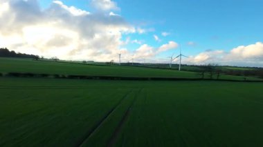 Kelmarsh Rüzgar Çiftliği 'ndeki rüzgar türbinlerinin insansız hava aracı görüntüsü, Northamptonshire' ın yuvarlanan yeşil tepelerinin üzerinde altın fırtınalı ışıkta yakalandı..