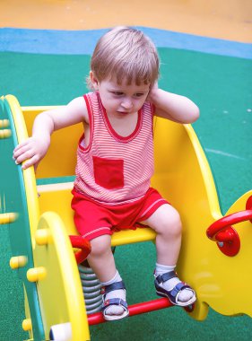 Küçük sarışın Çocuk Bahçesi üzerinde sallanan bir sarı sandalyede otururken cep telefonu üzerinde konuşurken