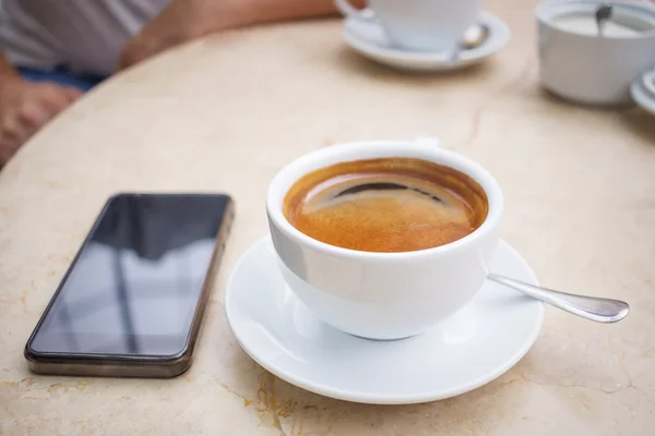 Phone and cup of coffee on marble table — Stock Photo, Image