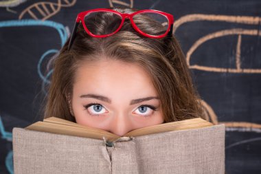 Genç öğrenci kız bir kitap saklanıyor suçlu gözüyle