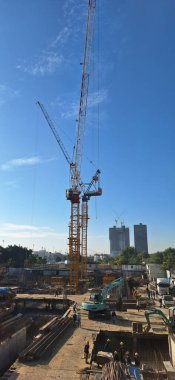 Şehirde inşaat alanı, vinç, işçiler.