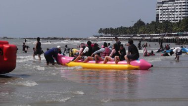 Seyahat edenler, 25 Şubat 2026 'da Tayland' ın Chon Buri şehrindeki Bangsaen Sahili 'nde deniz suyunda yüzme ve jet ski muz teknesi oyunu oynamak için ziyaret ederler.