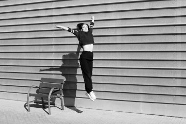 Şehir ortamında çağdaş bir dans dansçısının hareketini donduran siyah ve beyaz enstantane.