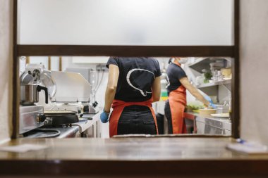 Coronavirus 'a karşı tedbir olarak bir maske ile korunan bir restoranda yemek pişirir. Kullanılan konteynırlar gübrelenebilir..