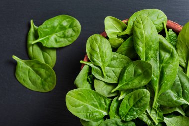 Tahta kase ve taze ıspanak. Siyah tahta kaplama arka planda.