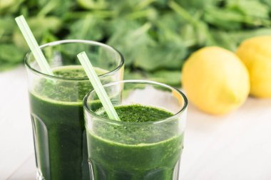 Limon suyu ile ıspanak beyaz ahşap masa üzerinde saman ile meşrubat kavanozu