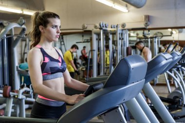 Spor salonunda koşu bandıyla kız eğitimi.