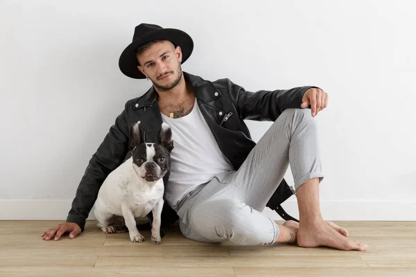 Hipster boy with leather jacket and hat next to his pet, a French Bulldog dog on white background