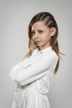 Studio portrait of a cute angry girl with long blonde hair wearing a white shirt against neutral background