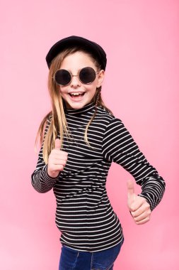 Studio portrait of happy girl wearing sunglasses against pink background