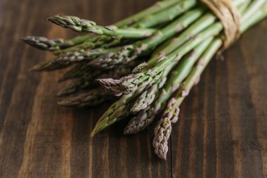 Bunch of raw fresh asparagus on wooden table. Focus on foreground.