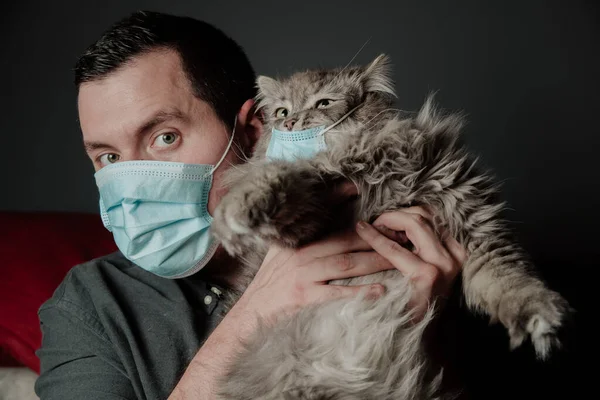 a man in a medical mask with a big cat in medical mask