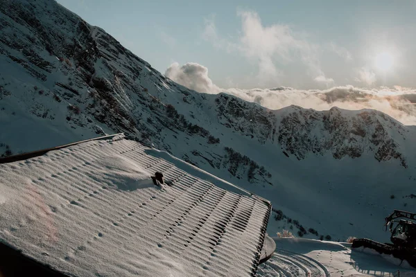 Adler, Rosa Khutor. Dağların yüksek kesimlerinde bulunan bir evin çatısı. Alçak bulutlar, gün batımı