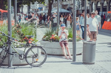 ALMANY, MUNICH - 25 Temmuz 2013: Yoğun bir caddede bir çocuk cep telefonuna bakar, yakınlarda bir bisiklet vardır