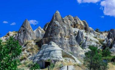 Türkiye 'nin Kapadokya kentinin yakınlarındaki göz kamaştırıcı renkli vadilerin önündeki taş evlerle Greme' e fantastik bir manzara